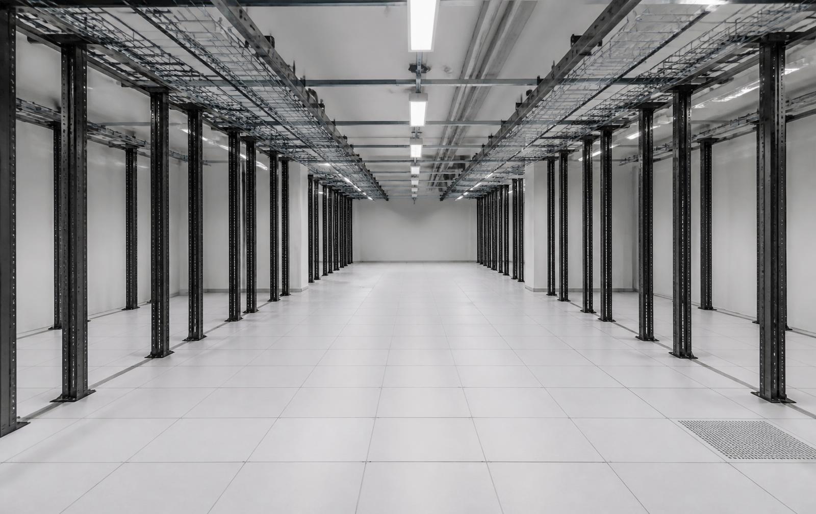A decommissioned server room with empty rack rails and open cable trays